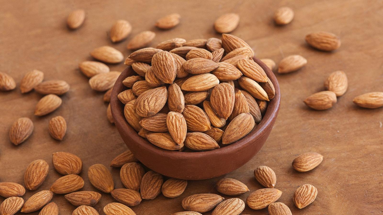 Almendras orgánicas en un cuenco de greda sobre madera
